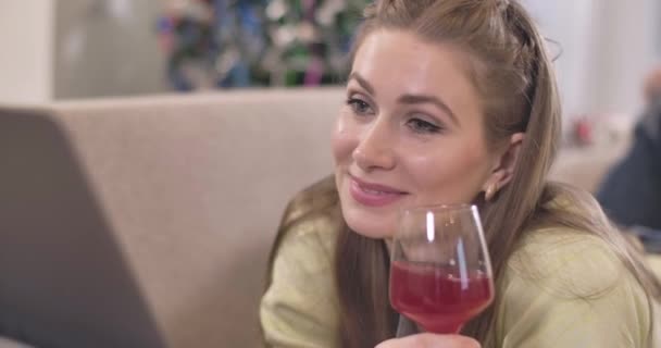 Close-up portret van gelukkige jonge blanke vrouw surfen op internet op laptop en het drinken van rode wijn. Mooie vrolijke dame die geniet van het kerstweekend alleen. Cinema 4k ProRes Hoofdkwartier. — Stockvideo