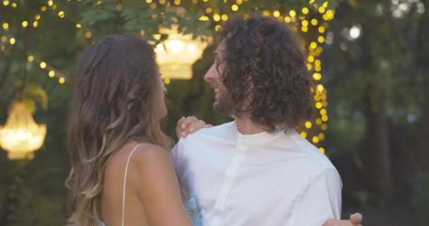 Närbild av glada romantiska par dans på sommaren kväll utomhus och leende. Porträtt av lycklig vit man och kvinna som dejtar utomhus i skymningen. Bio 4k ProRes HQ. — Stockvideo