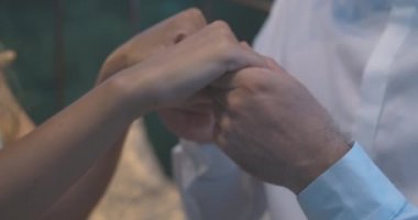 Alacakaranlıkta beyaz bir kadının elini öpen tanınmayan bir adamın yakın çekimi. Romantik genç çiftlerin yaz akşamları dışarı çıkmalarına bayılırlar. Sinema 4k ProRes Merkezi.