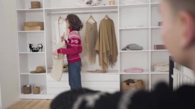 Hasır şapka giyen gülümseyen genç bir kadının geniş açılı portresi baş parmaklarını gösteren bulanık bir adam olarak. Neşeli kız arkadaş yılbaşı arifesinde erkek arkadaşına Noel kıyafeti gösteriyor..