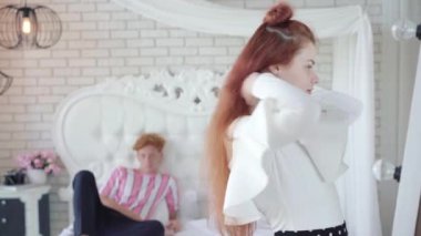 Genç, güzel, kızıl saçlı bir kadın arka planda bulanık bir erkek gibi giyinmeyi seçiyor. Kızgın kız arkadaşın portresi ve destekleyici erkek arkadaşın değil..