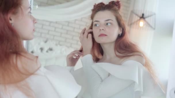 Refleksi di cermin dari wanita muda berambut merah cantik dengan blus putih menyesuaikan makeup. Wanita bergaya Kaukasia yang cantik memilih pakaian. Konsep kecantikan dan mode. — Stok Video