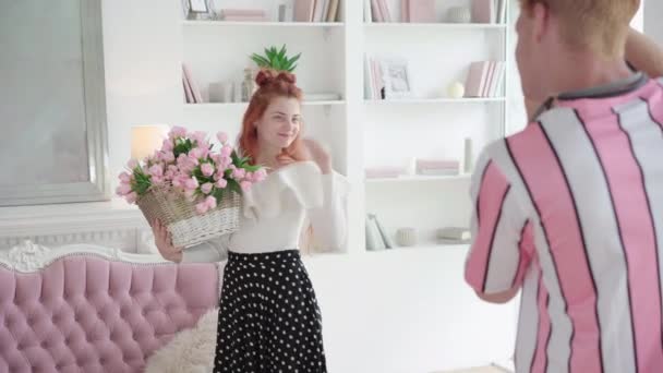 Hombre irreconocible tomando fotos de pelirroja hermosa mujer posando con cesta de flores. Retrato de la joven y feliz novia caucásica sosteniendo ramo como novio fotografiándola. — Vídeo de stock