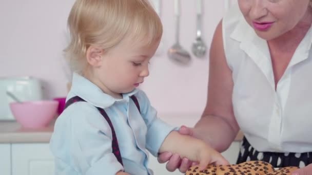 Opiekuńcza babcia daje słodkie ciasteczka słodkiemu chłopcu. Portret czarującego białego dziecka spędzającego weekendy z dziadkiem. Koncepcja rodziny i jedności. — Wideo stockowe