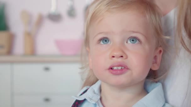 Cara de close-up de encantador menino loiro com olhos azuis mastigando biscoito. Retrato de criança branca bonito comer biscoito. Criança sorridente feliz desfrutando da infância. — Vídeo de Stock