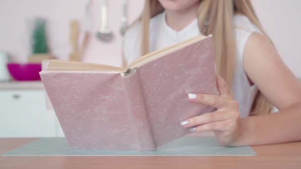 Неузнаваемая юная стройная белая женщина читает книги и пьет чай или кофе. Стильная красивая дама, наслаждающаяся счастливым утром с книгой на кухне. Хобби и стиль жизни. — стоковое видео