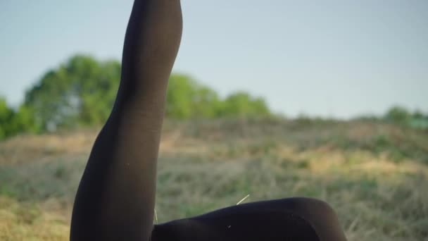 Камера рухається по гнучкому тілу молодої кавказької жінки в акробатичній позі, читаючи вголос на відкритому повітрі. Гарний гімнаст, що поєднує ранкове тренування та хобі на світанку.. — стокове відео