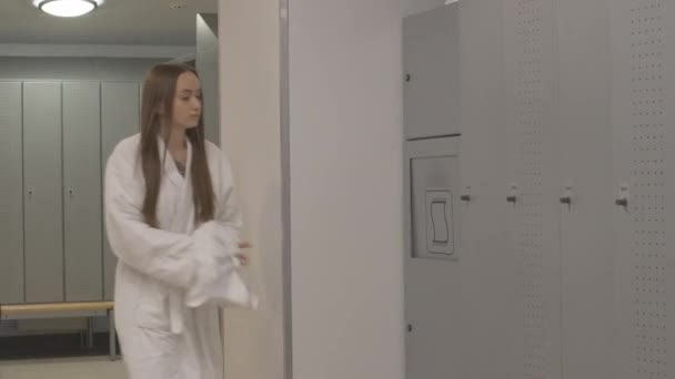 Ung idrottsman sätta använt hår handduk i handduk station och lämnar. Vacker vit kvinna i gym omklädningsrum efter träning eller träning. — Stockvideo