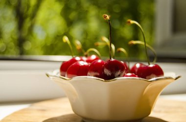 Olgun kırmızı, sulu, tatlı kiraz yeşil bir arka planda bir tabakta yatıyor.. 