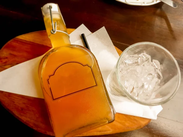 Citroen thee in een fles en een glas ijs op houten dienblad — Stockfoto
