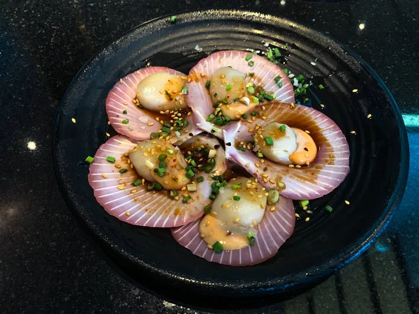 Fresh raw scallops in shell on a black dish — Stock Photo, Image