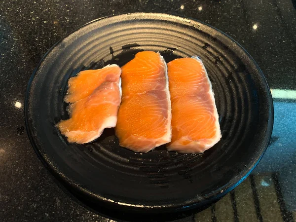 Raw salmon filet on black dish in restaurant — Stock Photo, Image
