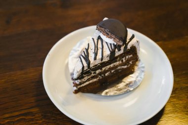 Ahşap masa üzerinde beyaz bir tabakta çikolatalı kek.