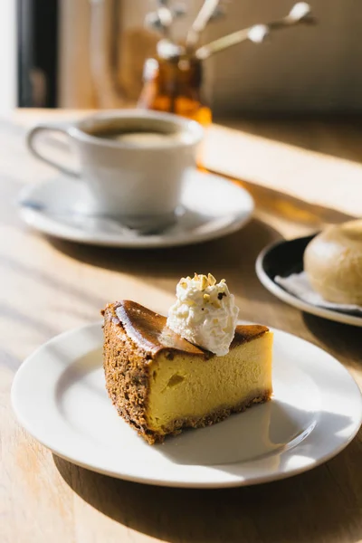 Öğleden sonra ışık ile ahşap masada kahve fincanı ve kabak pasta.