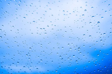 Arka plan için mavi gökyüzü ile cam su damlaları.