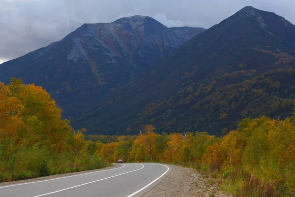 Autumn picturesque road with dark mountains, volcanoes and yellow trees. — Stock Photo, Image