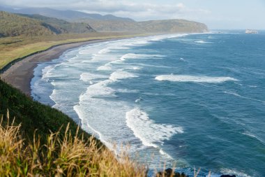 Rusya 'nın Kamçatka Yarımadası' ndaki uçurumların kenarından güzel bir okyanus manzarası. Pasifik Okyanusu 'nun derin mavi deniz suyu, siyah kumlu plaj, dağlar ve sonbahar manzarası, doğa duvar kağıtları.
