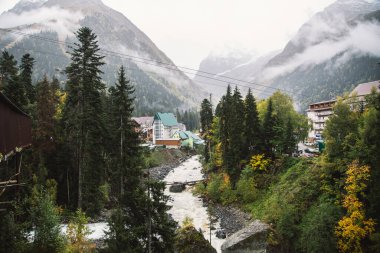 Sonbahar sezonunda Dombay kayak merkezi, Amanaus nehri manzarası ve köy, Kafkasya, Rusya 'daki köprüden karlı dağlar