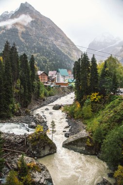 Sonbahar sezonunda Dombay kayak merkezi, Amanaus nehri manzarası ve köy, Kafkasya, Rusya 'daki köprüden karlı dağlar