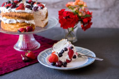 Angelcığım kek güzel bir dilim çırpılmış krema ve taze renkli meyveleri, çiçek ve meyve ile kaplı