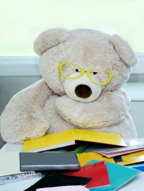Bear with big glasses reads a stack of colorful books. reading is power! clipart
