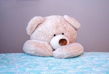 Big teddy bear kneels beside the bed for evening prayers clipart