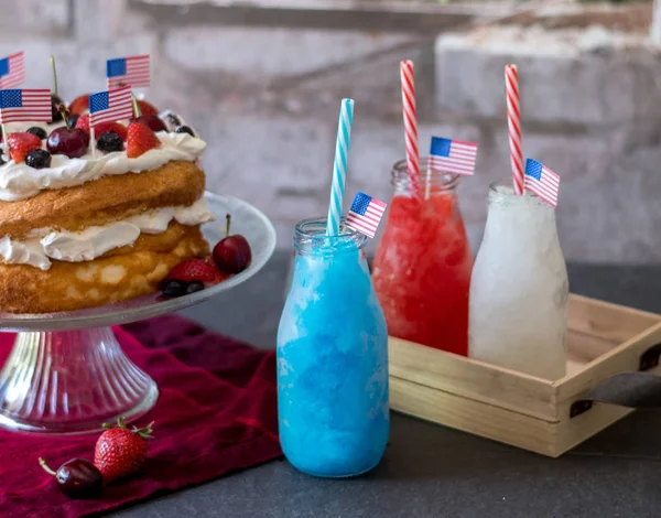 Red white and blue frozen drinks and  patriotic angel food cake with blueberries cherries and strawberries.  Happy 4th of july