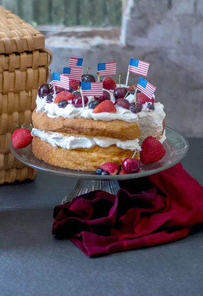 Patriotic angelfood cake with red white and blue berries and little American flags
