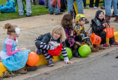 27 Ekim 2018 Coloma Mi ABD; bir satır çocukların eğlenceli Halloween kostüm giymiş, başlatmak bir olayı beklenirken bir kaldırıma oturmak