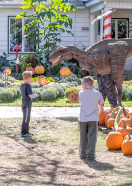 28 Eylül 2018, üç oaks Michigan A.b.d.; bir adam bir dinozor kostüm onları yerel bir kabak çiftlik kovalayan gibi genç erkek gülmek