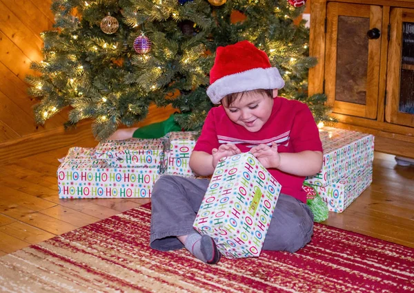 Junge öffnet ein Weihnachtsgeschenk — Stockfoto