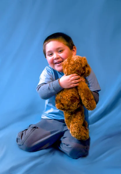 Young boy hugs a stuffed teddy bear