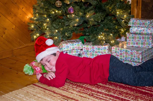 Menino dormindo debaixo da árvore de Natal — Fotografia de Stock