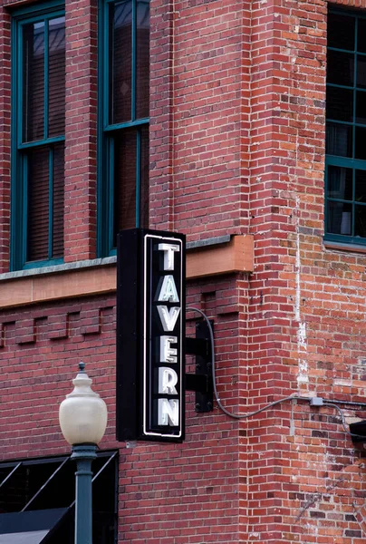 Tavern sign against a brick building exterior — Stock Photo, Image