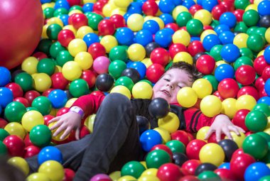 genç çocuk renkli topları büyük bir yığın yatıyor