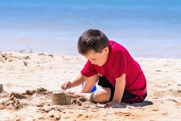 Niño construyendo un castillo de arena en la playa — Foto de Stock