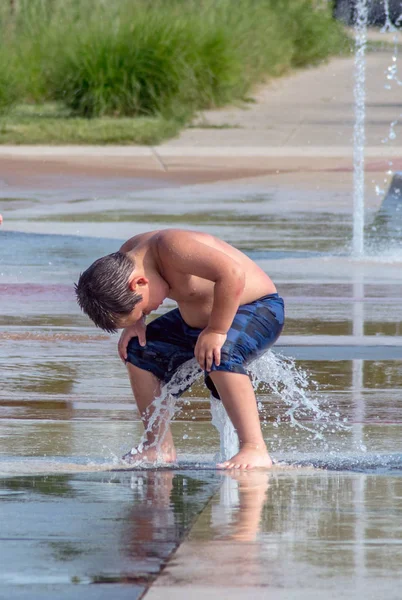 Chlapec sedící na vodní fontáně — Stock fotografie