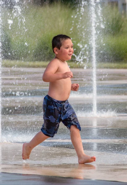 Aktiver Junge spielt in Springbrunnen — Stockfoto