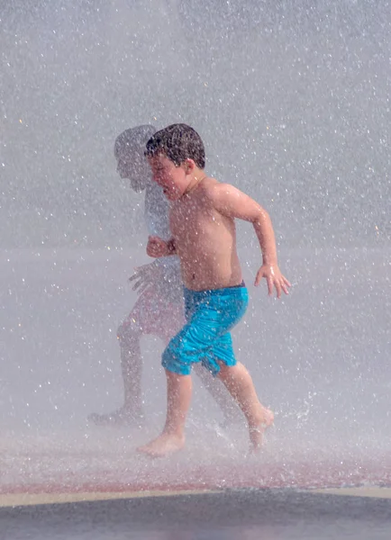 Two boys race through a summertime fountain — Stock Photo, Image