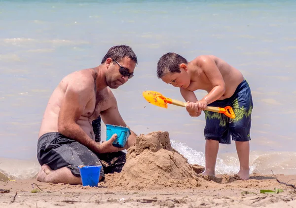 Pai e filho construindo castelos na praia — Fotografia de Stock
