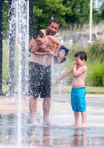 Padre e hijos en una fuente húmeda y fresca — Foto de Stock