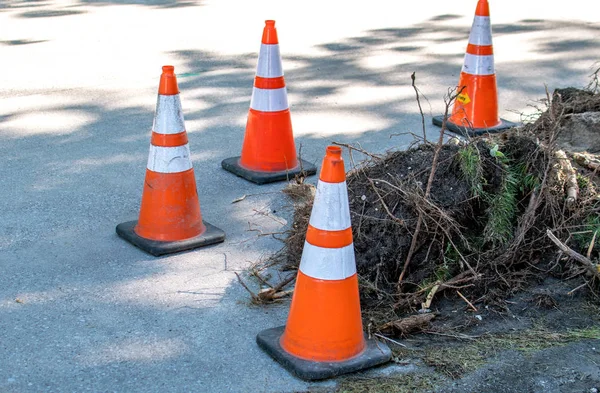 Cones de segurança guardam um buraco aberto em uma estrada local — Fotografia de Stock