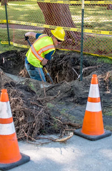 Arbeiter gräbt unter der Erde, um Kabel zu reparieren — Stockfoto