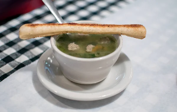 Italian wedding soup with a bread stick