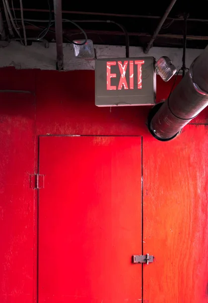 Znak wyjścia awaryjnego na czerwonym drzwiach — Zdjęcie stockowe