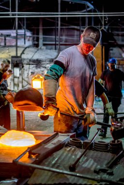 Bir dökümhane işçisi erimiş camla çalışır.