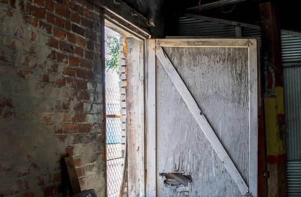 Old, broken wood door in a brick building — Stock Photo, Image
