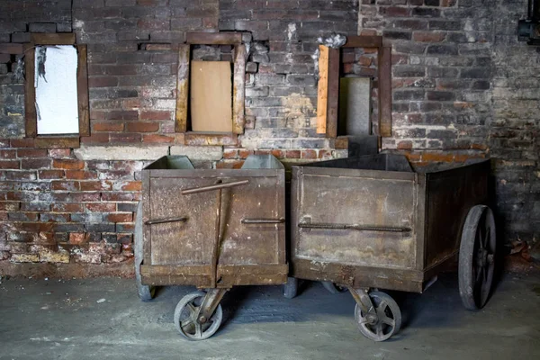 Old metal carts in a spooky brick warehouse — Stock Photo, Image