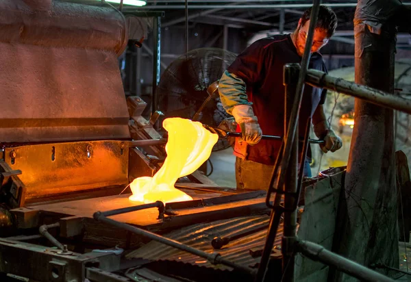 Glasarbeiter mischt geschmolzenes Glas in einer Glasfabrik — Stockfoto