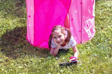 bir tablet ile pembe bir çadırda güzel küçük kız